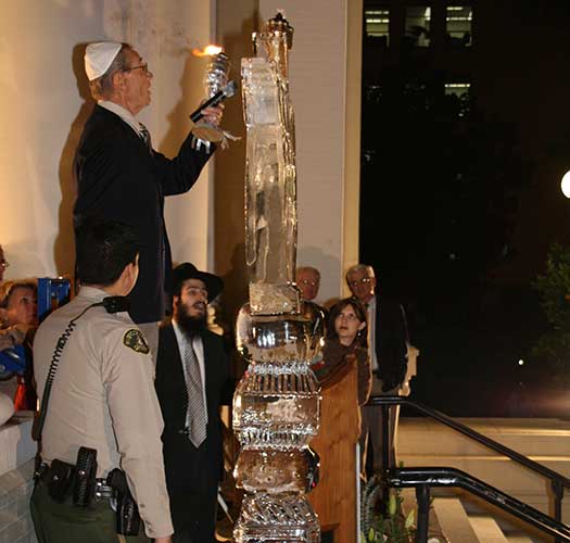 Leon Leyson lighting Menorah at Chabad of Riverside with Rabbi Shmuel Fuss.