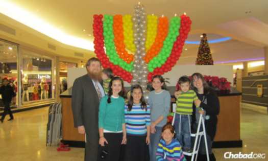 The Schmukler family gathers in front of a balloon menorah at a local mall during Chanukah.