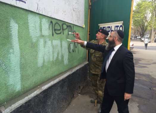 Chabad Shliach Rabbi Avrohom Wolf and a representative of Right Sector, a right wing political party, erase anti-Semitic graffiti that spells "death to the Jews" in Odessa.