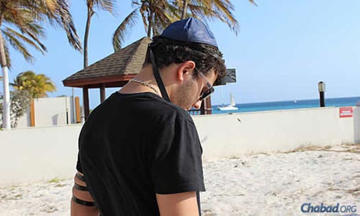 At a Lag BaOmer barbecue on the beach, Jon Atias performs the mitzvah of wrapping tefillin.