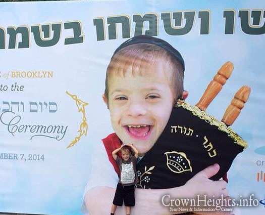 Boruch Shneur Chein poses in front of a banner outside the JCM.
