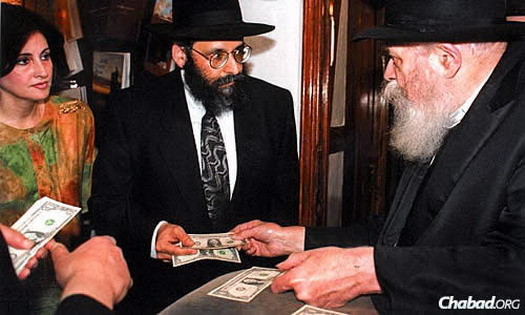The Lipskars receive a dollar from the Rebbe—Rabbi Menachem M. Schneerson, of righteous memory—in the Crown Heights neighborhood of Brooklyn, N.Y. The Rebbe had earlier given them a blessing to move to the village of Bal Harbour, which was once restricted to Jews.