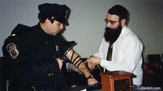 Rabbi Shalom Paltiel assists an officer with the putting on of Tefillin (Photo: Lubavitch Archives).