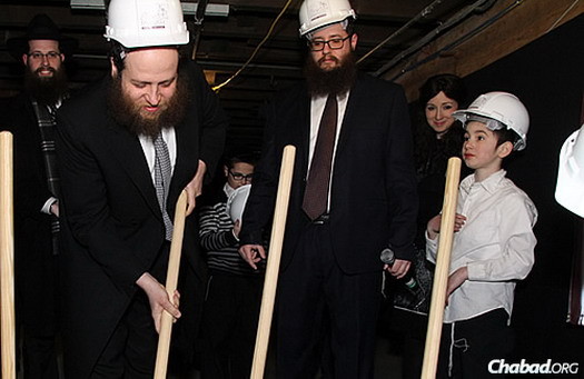 Rabbi Baruch Hertz, left, director of Chabad of Lakeview and Congregation B'nei Ruven in Chicago, takes a stab at some dirt at a Feb. 20 event across from the old mikvah site and celebrating the groundbreaking of a new one.
