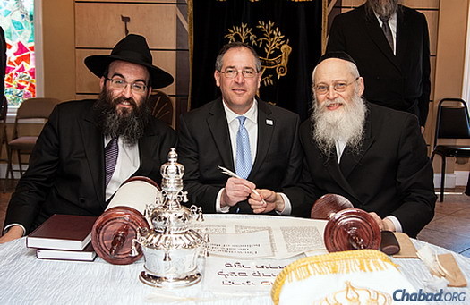 Rabbi Hirshy Minkowicz, left, joins Mike Bodker, the Jewish mayor of Johns Creek, Ga., and scribe Rabbi Moshe Klein in writing a letter in the Torah scroll dedicated to Rashi.