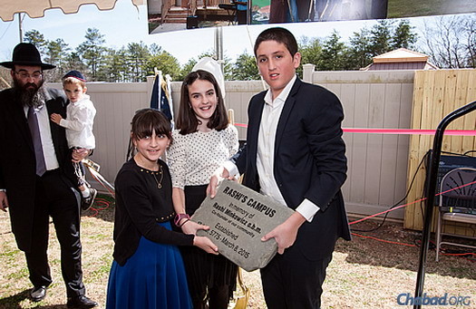 Tonia, Henya and Yoel Minkowicz lay the cornerstone of the new facility, “Rashi’s Campus.” At the far left is Rabbi Minkowicz, holding the family's youngest child, Alter.