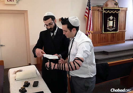 Rabbi Yehuda Ceitlin, outreach director of Chabad Lubavitch of Tucson and associate director of the congregation, wraps tefillin with Justin Schecker, a reporter for KGUN 9 television news.