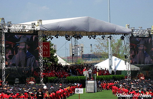 Dr. Binyomin Abrams, a senior lecturer of chemistry in the College of Arts & Sciences at Boston University, won the school's Metcalf Award for Excellence in Teaching. He is shown on jumbo screens on the right and left at commencement on Sunday, when he was presented with the honor.