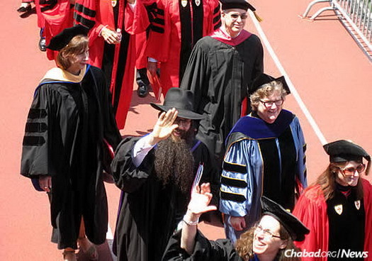 Giving a wave to the crowd on May 17 during Boston University's graduation ceremony, where he walked with other colleagues.