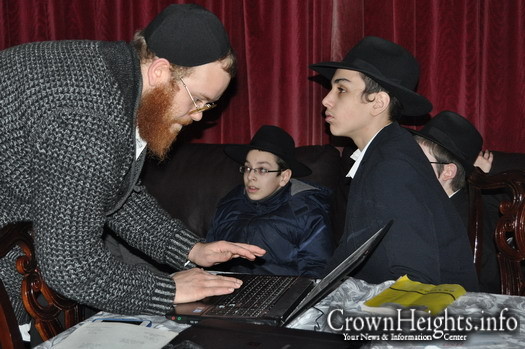 Rabbi Mendy Mochkin, JEM's lead interviewer, scanning letters while Manchester Yeshiva students look on.