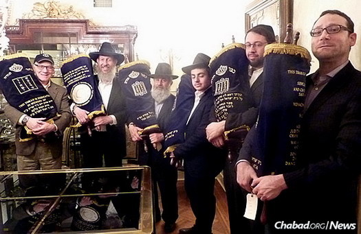 Rabbi Bentzion Chanowitz, second from left, along with those involved in the project display the refurbished Torahs before they are sent on loan to their new homes.