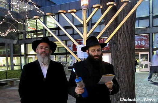 Rabbi Shmuel Posner, left, director of the Chabad House of Greater Boston, with Abrams lighting a public menorah during Chanukah 2011.