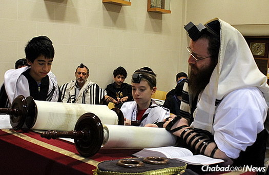 Shacharit morning prayers at Wolfsohn. Gurevitch, right, reads from the Torah as a student receives an aliyah.