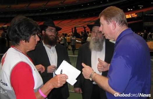 Rabbi Mendel Rivkin, left, and Rabbi Zelig Rivkin, shown 10 years ago in Houston's Astrodome consulting with authorities on identifying Jews who were stranded as a result of Hurricane Katrina.