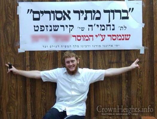 Nechemia Kirshenzaft posing in front of a sign celebrating his release.