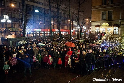 A crowd gathers in the rain to watch the public lighting of a giant menorah in St. Petersburg.