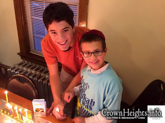 Mendel Tiechtel of Lawrence, KS lights Menorah with a student at a Fraternity on KU