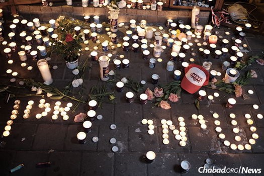 Israelis light candles on Saturday night spelling out the names of victims—“Shimi and Alon”—outside a pub on Dizengoff Street in central Tel Aviv.