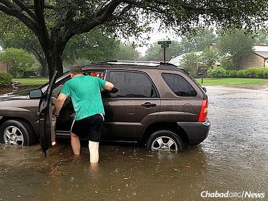 A man from the community talks to a driver that pulled onto his lawn to get out of the rising water.