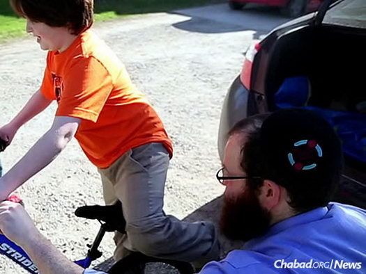 Rabbi Tzvi Schectman, family coordinator at the Friendship Circle in Michigan, delivers a bike to a child after last year’s annual “Great Bike Giveaway” national contest.