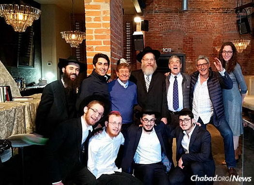 A group gathers days before the 2016 Berkshire Hathaway Annual Shareholders Meeting in a local bar that served as a makeshift shul/Chabad Center in Omaha. Top, from left: Avraham Kenner, Andrew Greenwall-Cohen, Arnold Basserabie, Rabbi Mendel Katzman, Gary Yarus, David Cicurel and Rochi Katzman. Bottom, from left: Zelig Katzman, Yossi Katzman, Yisroel Benshimon and Zalmy Cohen