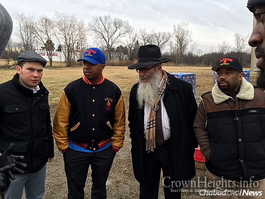 Rabbi Yisroel Weingarten, director of Chabad House Lubavitch of Eastern Michigan, back in March helping distribute bottled water to residents in need. Now, a free sponge can also aid those still grappling with water issues. With him, from left: Jewish boxer Dmitry Salita, and Detroit boxing trainers Javan “Sugar” Hill and Travone Chambers.