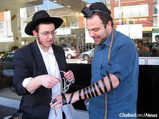 Taking time to wrap tefillin with Jewish men and boys over the age of 13