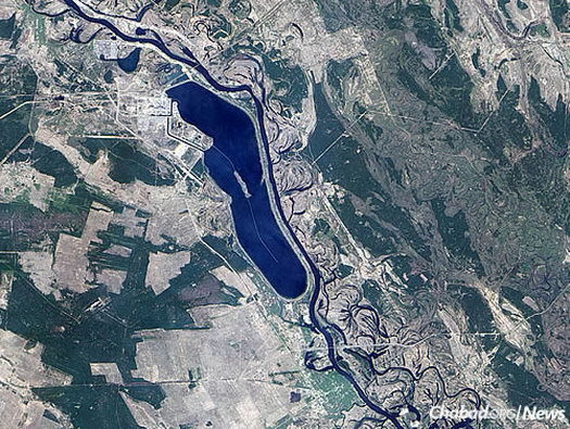 Aerial view of the reactor and its surroundings in April 2009. The large body of water in the left half of the image is the northwestern end of a 12-kilometer-long cooling pond; water channels run through the network of reactor-related buildings west of the pond.