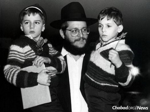 Rabbi Josef Aronov, chairman of Chabad in Israel, holds two recently arrived children.