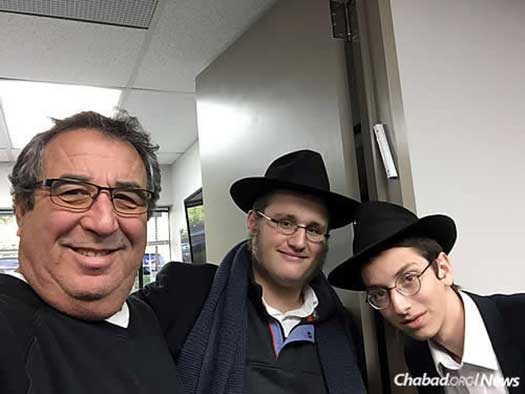 Mendel Azimov and Mendel Zaklikovsky put up a mezuzah on an office doorpost. They also make time to chat, answer questions and pose for a photo or two.