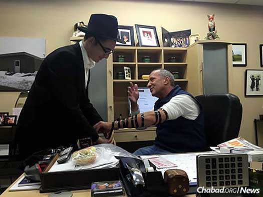 Mendel Gopin wraps tefillin with those on his Friday route . . .